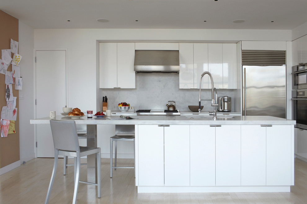Esempio di una cucina parallela design con ante lisce, elettrodomestici in acciaio inossidabile, ante bianche, paraspruzzi bianco e paraspruzzi in lastra di pietra
