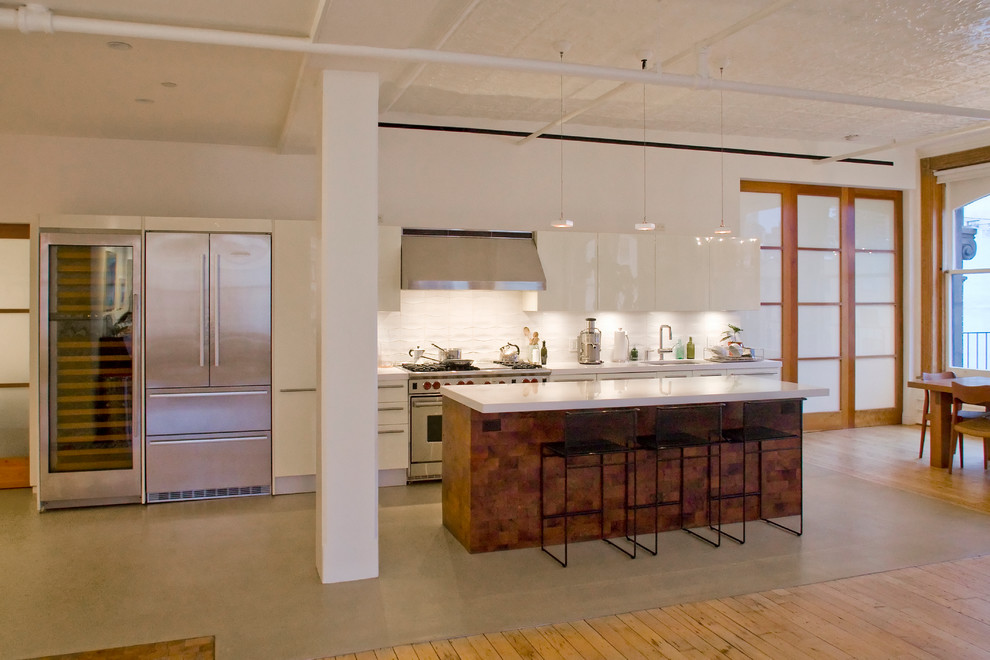 Стильный дизайн: параллельная кухня-гостиная в стиле лофт с плоскими фасадами, белыми фасадами и островом - последний тренд