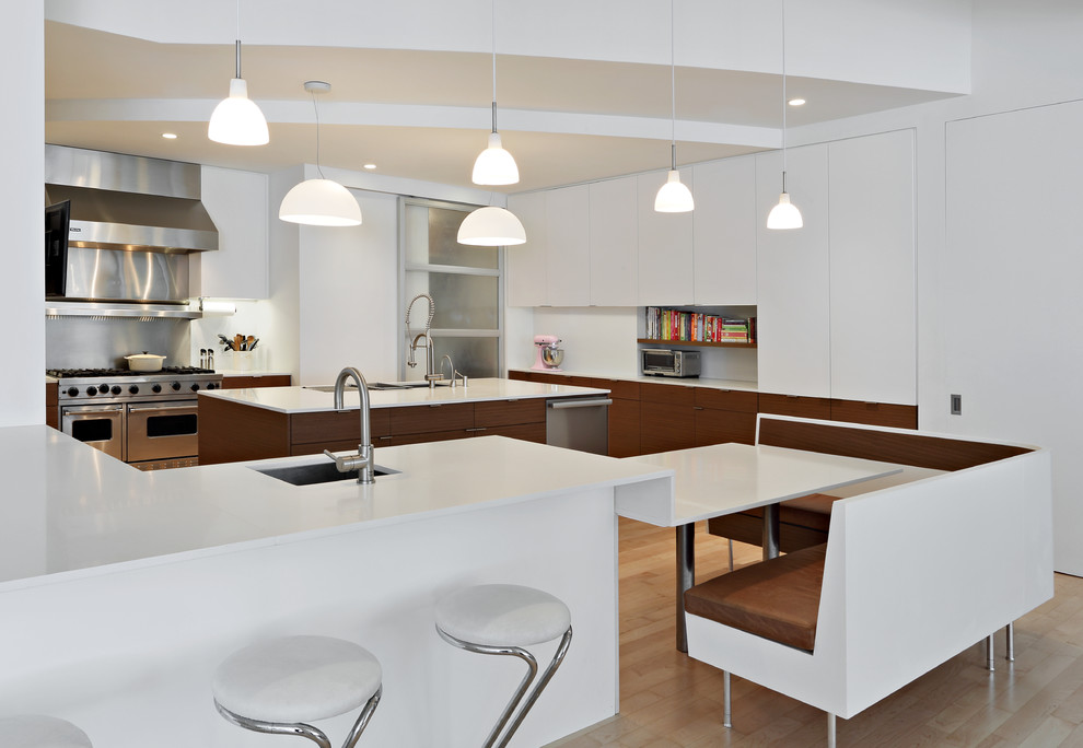 Inspiration for a large modern u-shaped light wood floor eat-in kitchen remodel in New York with an undermount sink, flat-panel cabinets, white cabinets, metallic backsplash, stainless steel appliances, solid surface countertops, metal backsplash, an island and white countertops