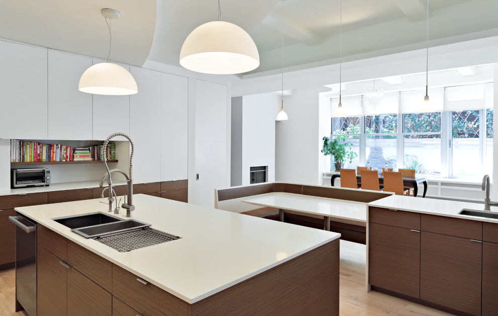 Large modern u-shaped kitchen/diner in New York with a submerged sink, flat-panel cabinets, white cabinets, composite countertops, metallic splashback, metal splashback, stainless steel appliances, light hardwood flooring and an island.