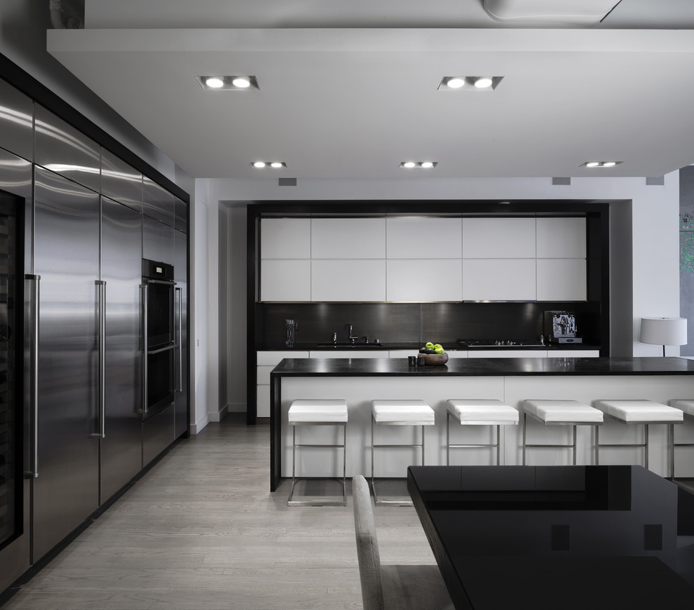 Ejemplo de cocina moderna con electrodomésticos de acero inoxidable, con blanco y negro y barras de cocina