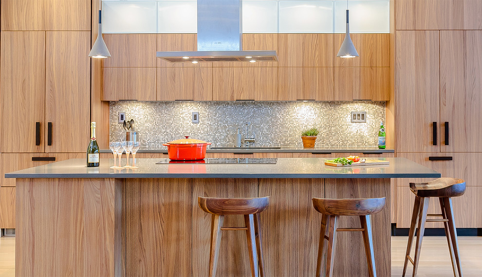 Modern inredning av ett kök, med släta luckor, skåp i mellenmörkt trä, flerfärgad stänkskydd, stänkskydd i mosaik, integrerade vitvaror, ljust trägolv och en köksö