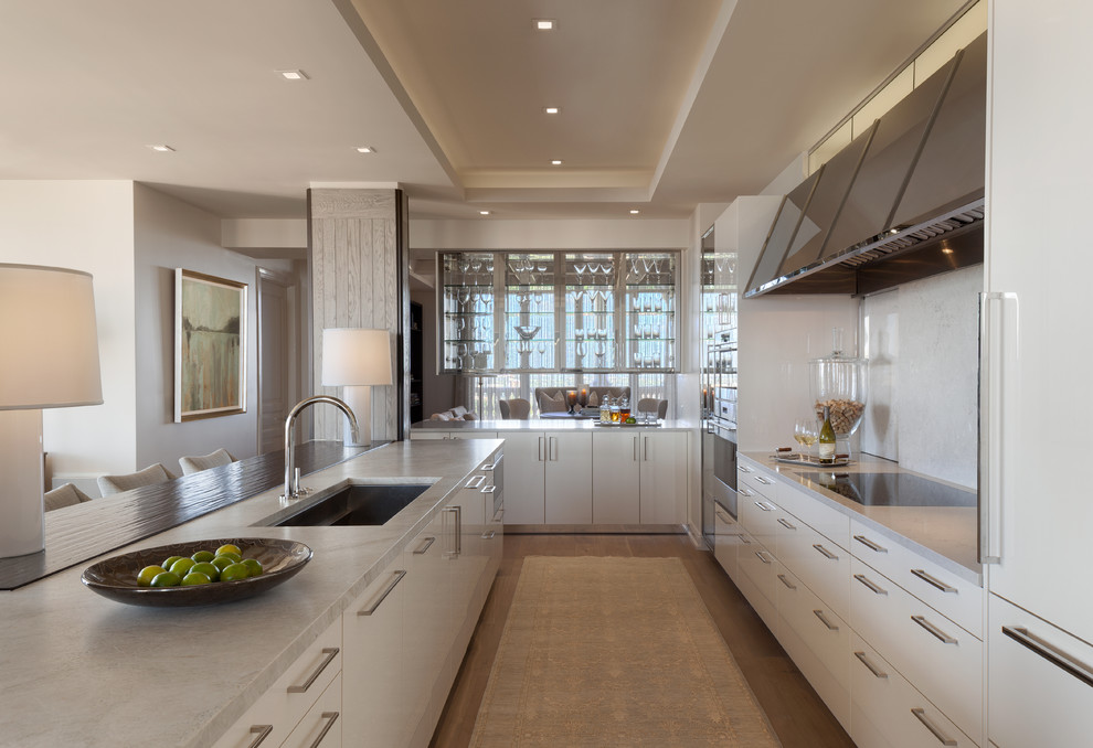 Inspiration for a large contemporary galley kitchen/diner in Tampa with flat-panel cabinets, white cabinets, an island, a submerged sink, white splashback and granite worktops.