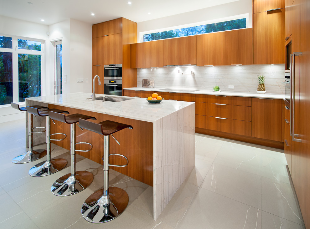 Foto på ett funkis l-kök, med en undermonterad diskho, släta luckor, skåp i mellenmörkt trä, rostfria vitvaror och vitt stänkskydd