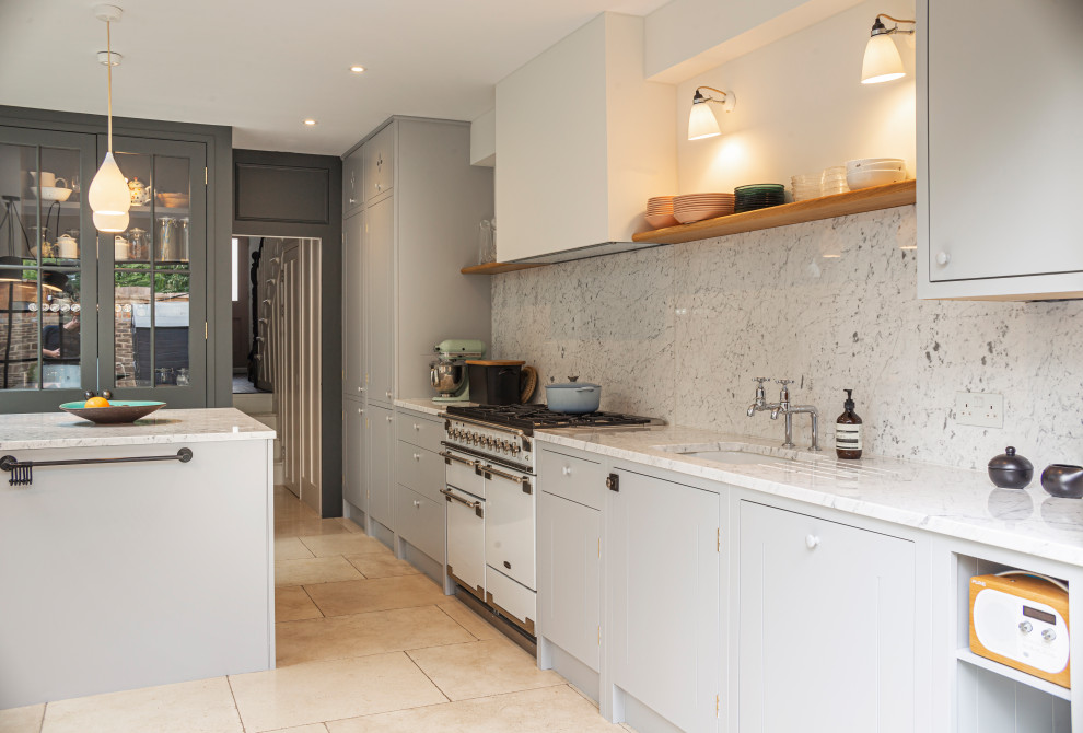 Photo of a classic galley kitchen in London with a submerged sink, flat-panel cabinets, grey cabinets, grey splashback, stone slab splashback, white appliances, an island, beige floors and grey worktops.