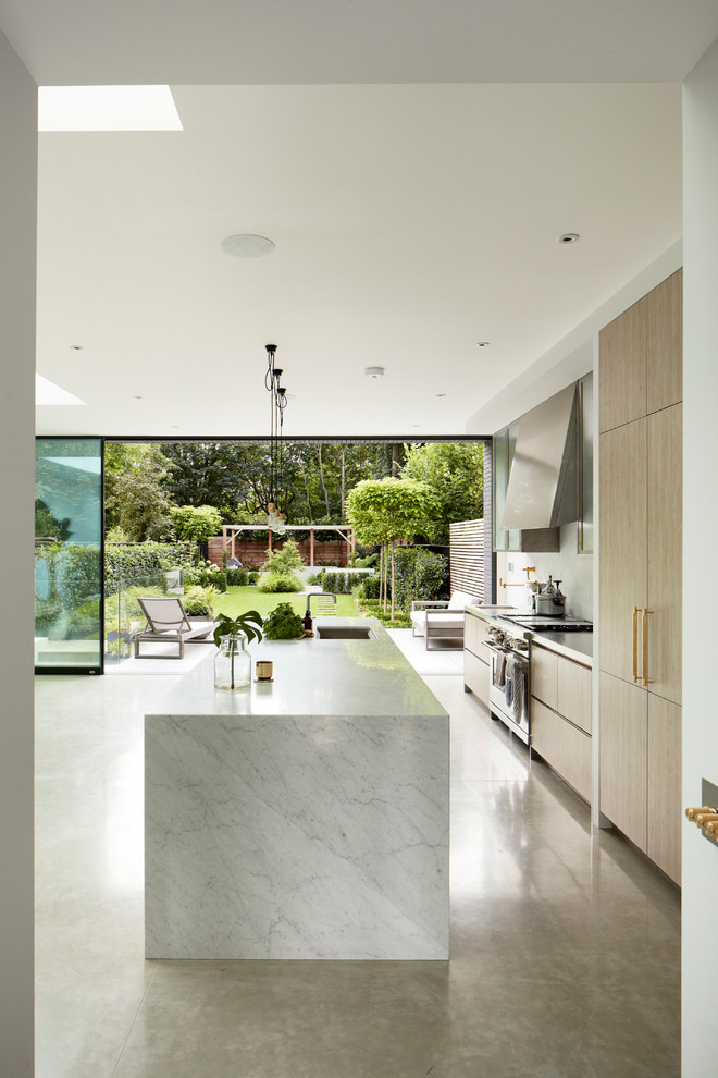 Inredning av ett modernt kök med öppen planlösning, med marmorbänkskiva, vitt stänkskydd, rostfria vitvaror, betonggolv och en köksö
