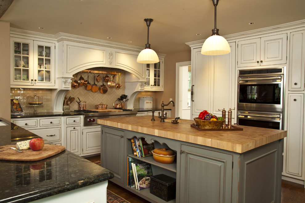 Ejemplo de cocina rústica de obra con electrodomésticos con paneles, salpicadero de azulejos tipo metro y encimera de madera