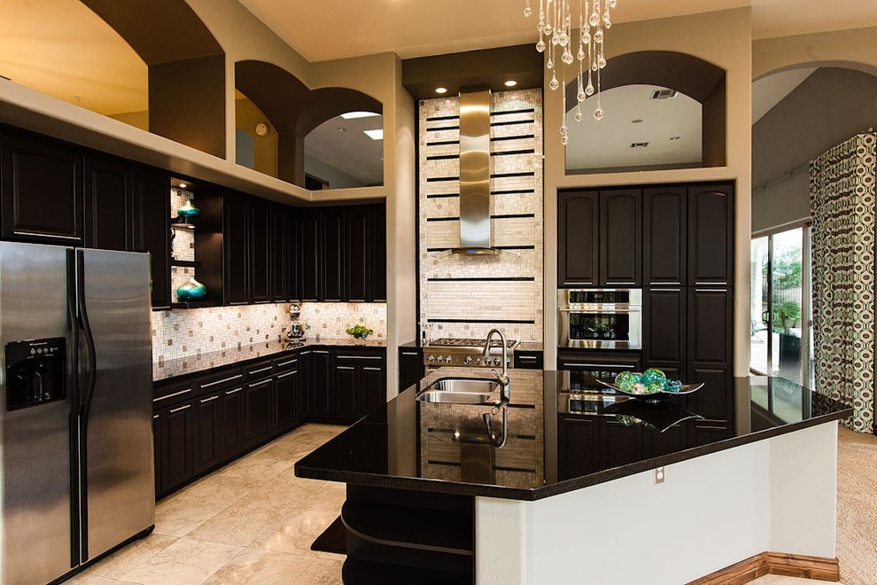 Bild på ett mycket stort funkis kök, med en undermonterad diskho, luckor med upphöjd panel, svarta skåp, granitbänkskiva, vitt stänkskydd, rostfria vitvaror, travertin golv och en köksö