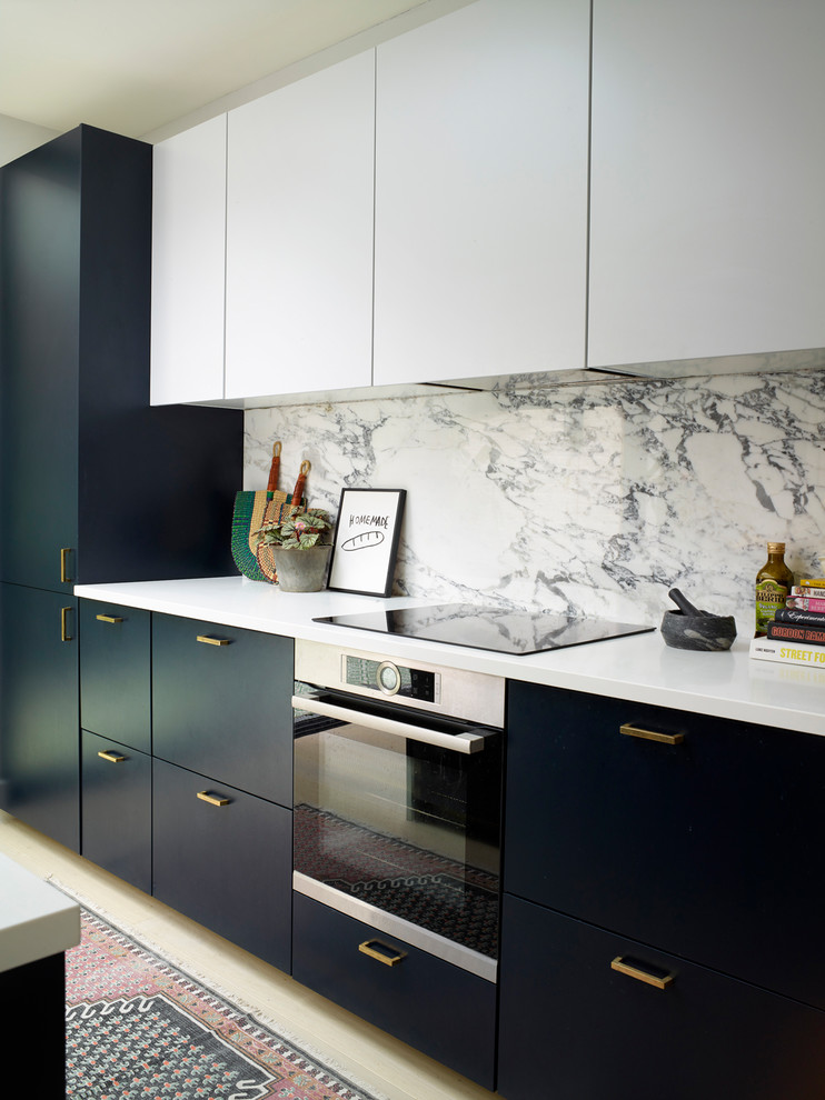 Photo of a medium sized contemporary single-wall open plan kitchen in London with a built-in sink, flat-panel cabinets, blue cabinets, quartz worktops, grey splashback, marble splashback, black appliances, light hardwood flooring, an island, white floors and white worktops.
