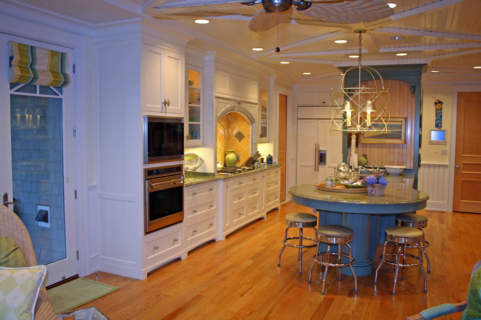 ボストンにあるトロピカルスタイルのおしゃれなキッチン (白いキャビネット、黄色いキッチンパネル、パネルと同色の調理設備) の写真