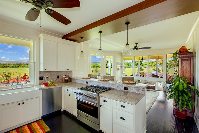 Bild på ett mellanstort tropiskt kök, med en rustik diskho, skåp i shakerstil, vita skåp, granitbänkskiva, brunt stänkskydd, stänkskydd i sten, rostfria vitvaror, mörkt trägolv och svart golv