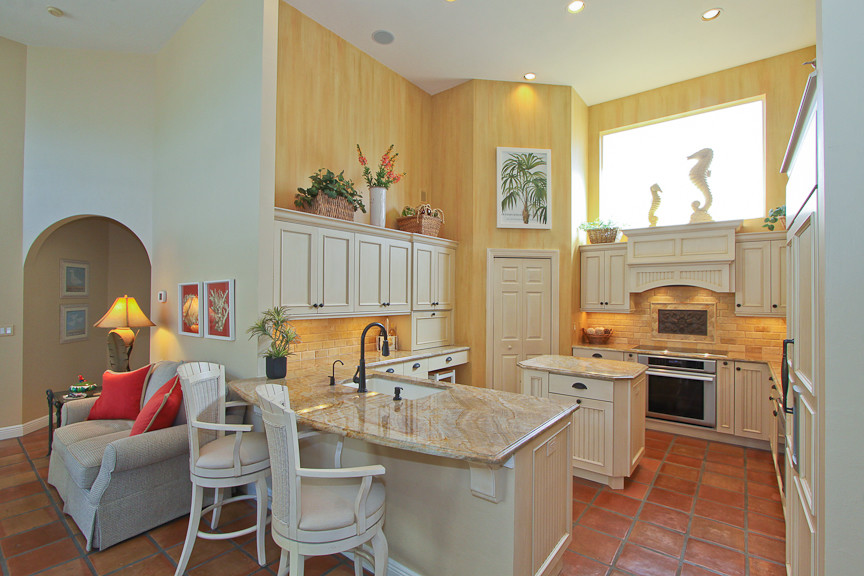 Exempel på ett stort exotiskt kök, med en undermonterad diskho, beige skåp, granitbänkskiva, flerfärgad stänkskydd, klinkergolv i terrakotta, luckor med infälld panel, integrerade vitvaror, brunt golv och en köksö
