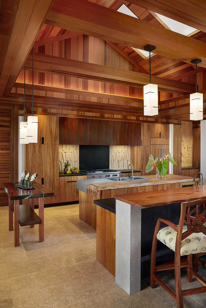 Photo of a large world-inspired galley open plan kitchen in Hawaii with an integrated sink, flat-panel cabinets, medium wood cabinets, wood worktops, multi-coloured splashback, integrated appliances, limestone flooring, multiple islands and limestone splashback.