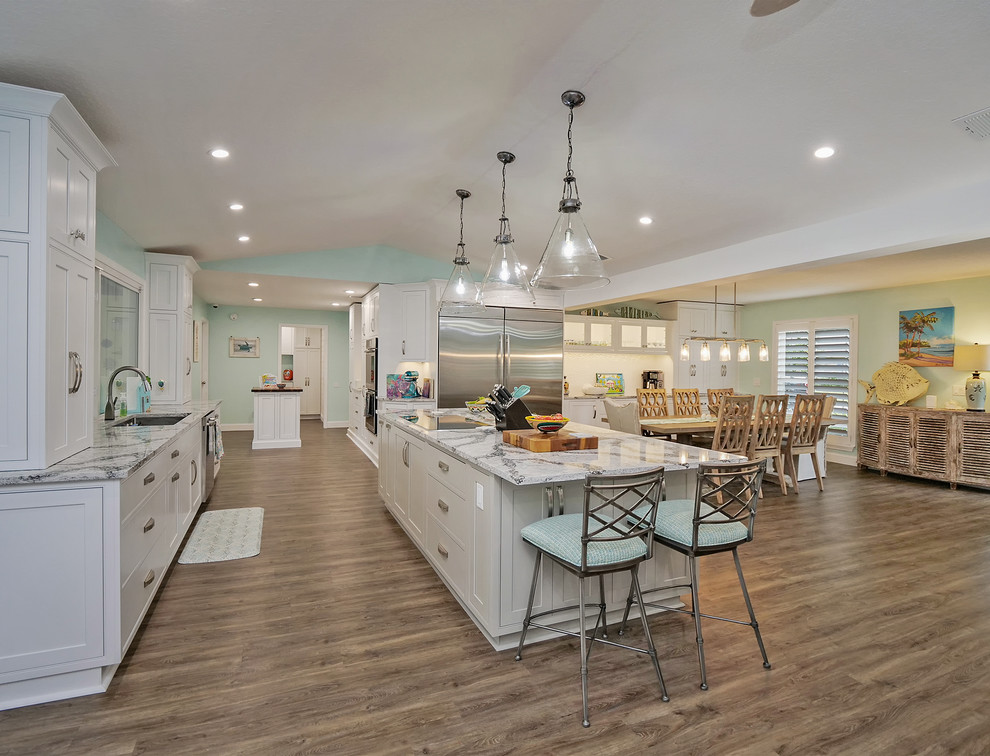 Open concept kitchen - large tropical vinyl floor open concept kitchen idea in Jacksonville with shaker cabinets, white cabinets, quartz countertops, white backsplash, ceramic backsplash, stainless steel appliances, two islands and gray countertops