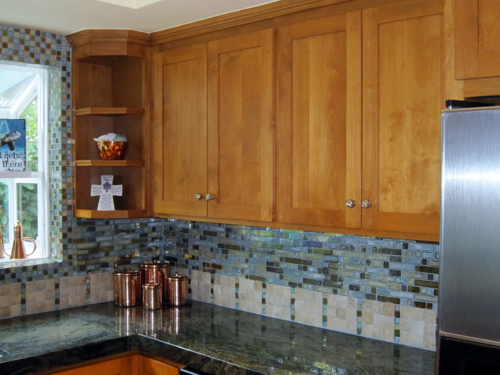 Island style kitchen photo in Los Angeles with glass sheet backsplash and stainless steel appliances