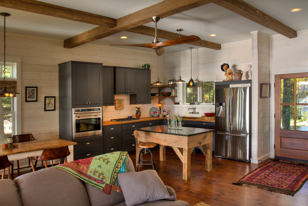 Rustic l-shaped open plan kitchen in Minneapolis with a submerged sink, shaker cabinets, grey cabinets, wood worktops, stainless steel appliances, medium hardwood flooring, an island and orange floors.