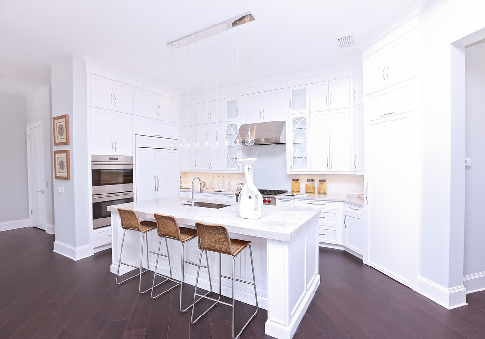 Exempel på ett mellanstort klassiskt kök, med en nedsänkt diskho, luckor med infälld panel, vita skåp, granitbänkskiva, vitt stänkskydd, rostfria vitvaror, mörkt trägolv och en köksö