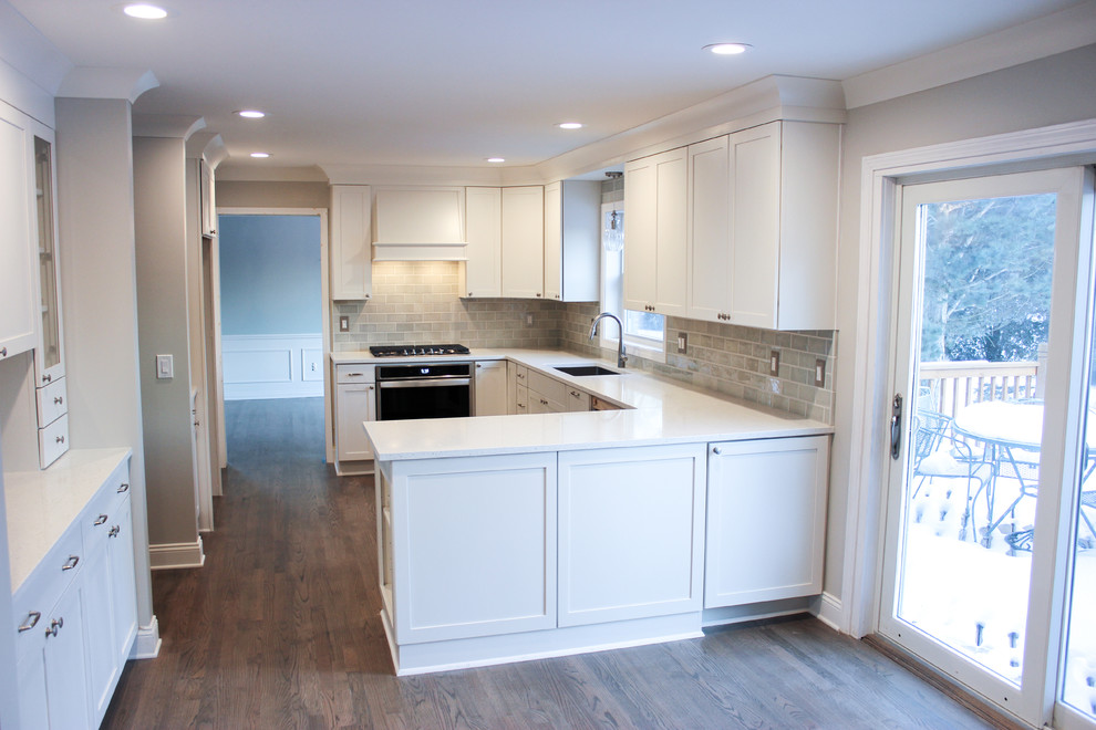 Bild på ett vintage vit vitt kök, med en undermonterad diskho, luckor med infälld panel, vita skåp, bänkskiva i kvarts, grönt stänkskydd, stänkskydd i keramik, rostfria vitvaror, mörkt trägolv och brunt golv