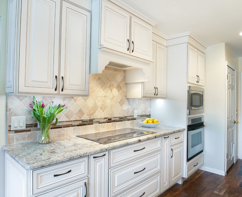 Klassisk inredning av ett stort beige beige kök, med en undermonterad diskho, luckor med upphöjd panel, vita skåp, granitbänkskiva, beige stänkskydd, stänkskydd i kalk, rostfria vitvaror, mellanmörkt trägolv, en köksö och brunt golv