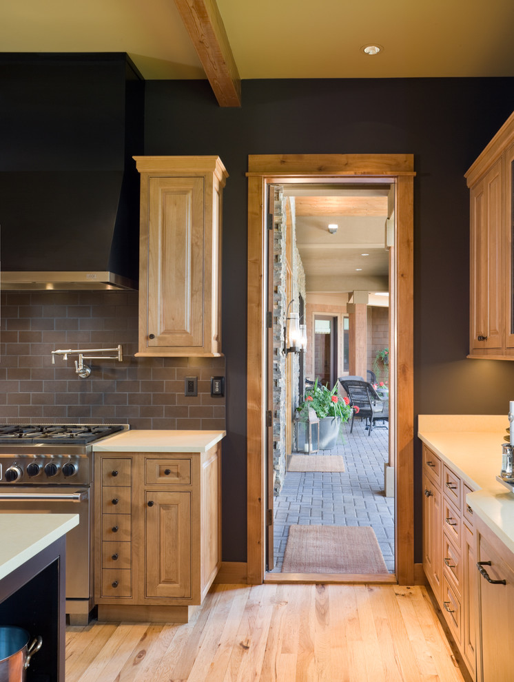 Exempel på ett rustikt kök, med luckor med upphöjd panel, skåp i ljust trä, brunt stänkskydd, stänkskydd i tunnelbanekakel och rostfria vitvaror
