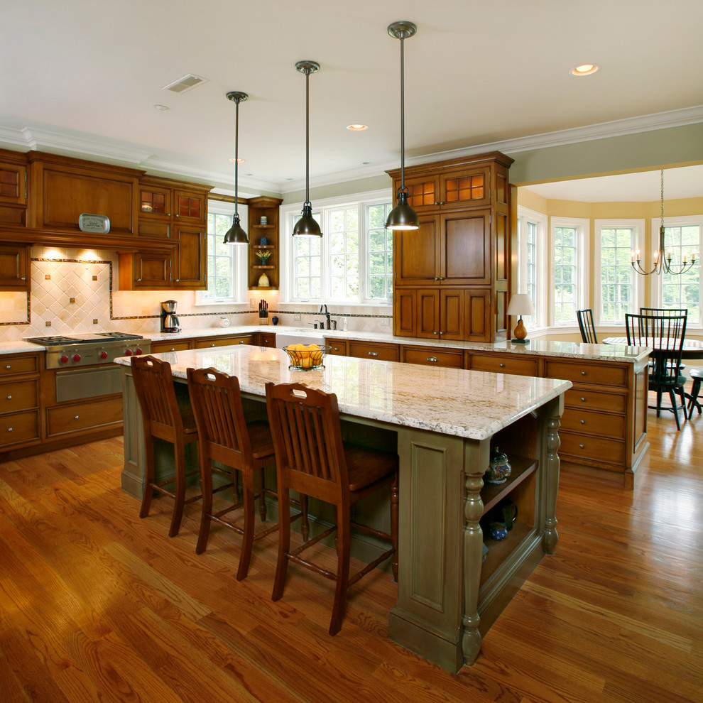 Lantlig inredning av ett kök, med en rustik diskho, luckor med infälld panel, skåp i mörkt trä, granitbänkskiva, beige stänkskydd, mellanmörkt trägolv och rostfria vitvaror