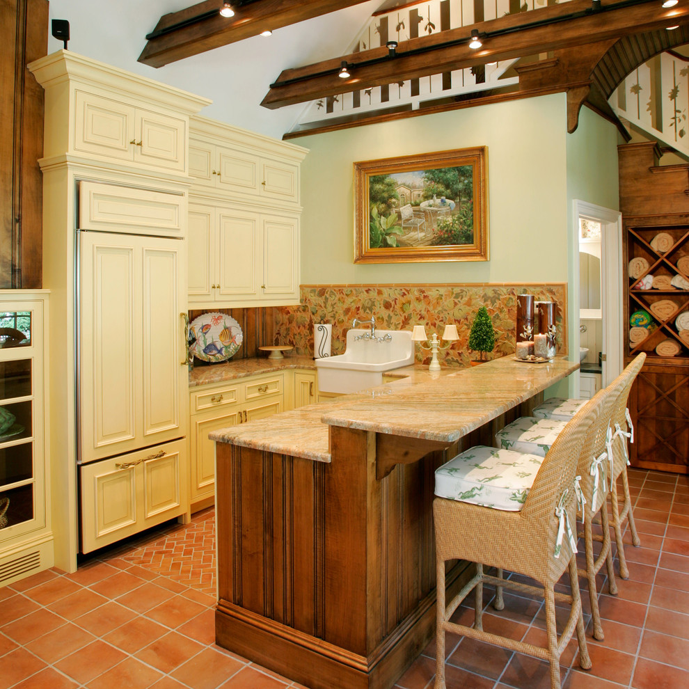 Inredning av ett lantligt flerfärgad flerfärgat kök med öppen planlösning, med en rustik diskho, luckor med infälld panel, beige skåp, granitbänkskiva, flerfärgad stänkskydd, integrerade vitvaror och klinkergolv i terrakotta