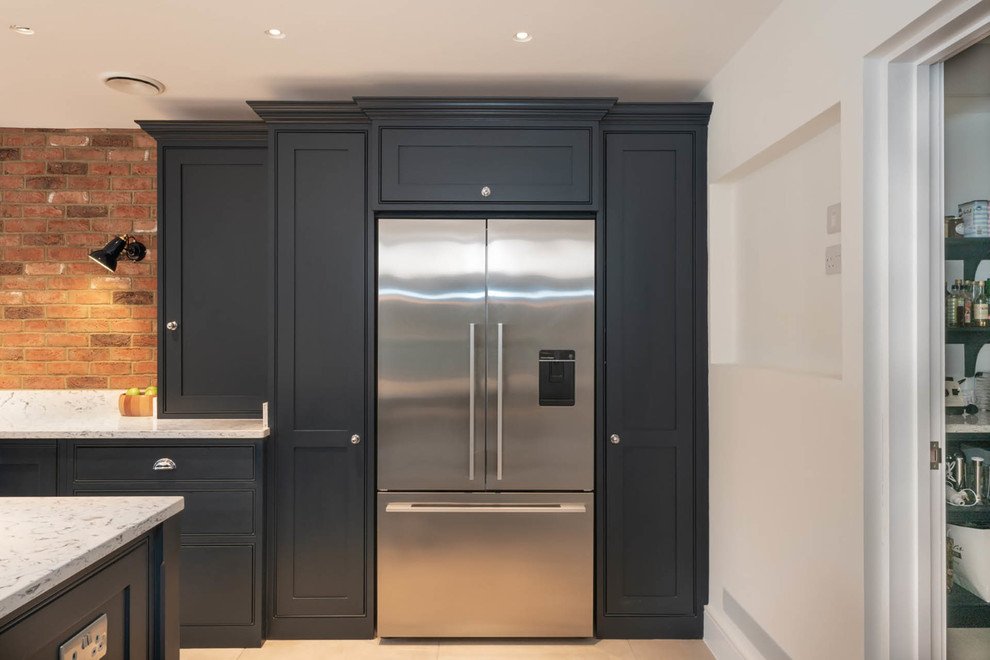 Design ideas for an expansive contemporary single-wall open plan kitchen in Essex with a belfast sink, beaded cabinets, blue cabinets, quartz worktops, multi-coloured splashback, brick splashback, stainless steel appliances, terracotta flooring, an island, beige floors and white worktops.