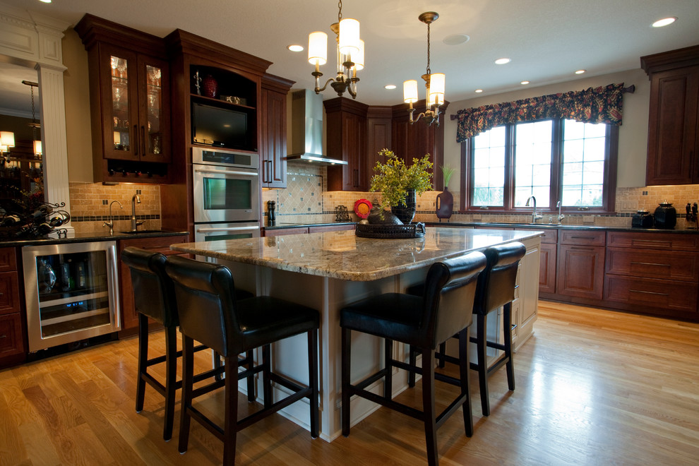 Example of a large classic l-shaped enclosed kitchen design in Other with raised-panel cabinets, dark wood cabinets, granite countertops, beige backsplash, stainless steel appliances and an island