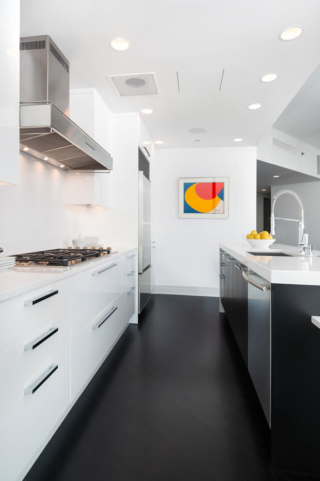 Inspiration for a small contemporary single-wall open plan kitchen in Chicago with a submerged sink, flat-panel cabinets, white cabinets, engineered stone countertops, white splashback, stainless steel appliances, dark hardwood flooring and an island.