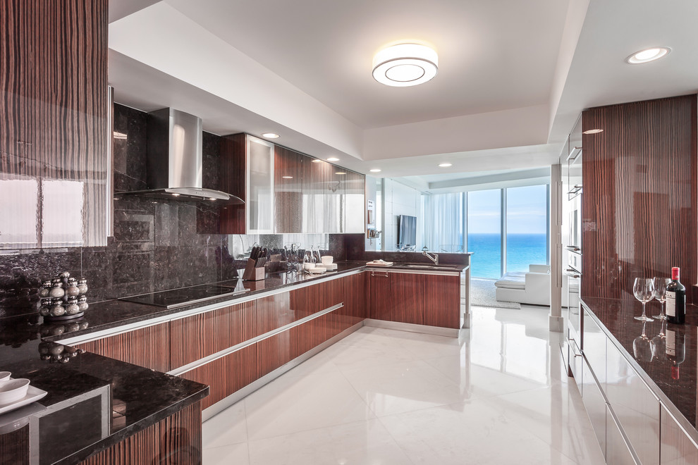 This is an example of a contemporary u-shaped kitchen in Miami with flat-panel cabinets, dark wood cabinets, black splashback, stone slab splashback and no island.