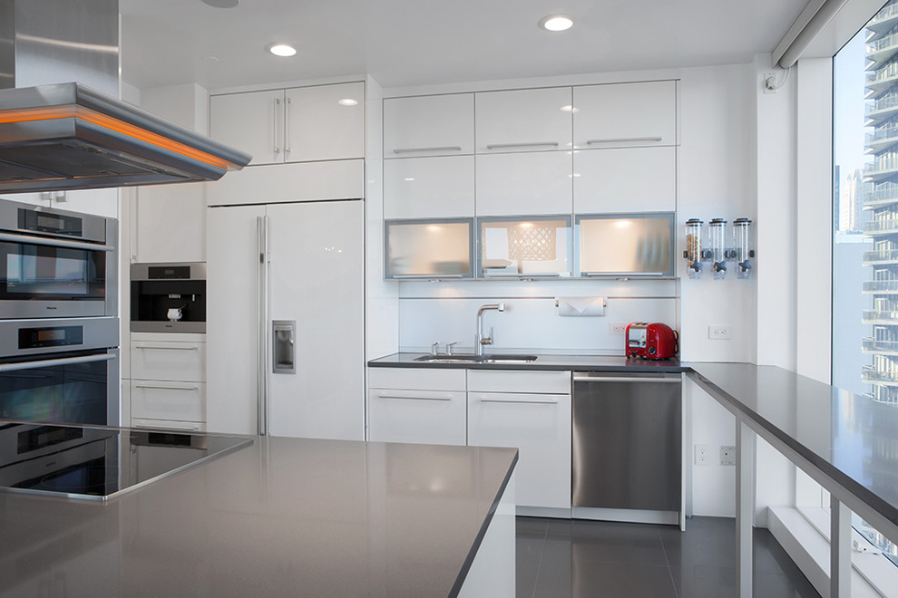 Photo of a contemporary u-shaped kitchen in New York with a double-bowl sink, flat-panel cabinets, white cabinets and stainless steel appliances.