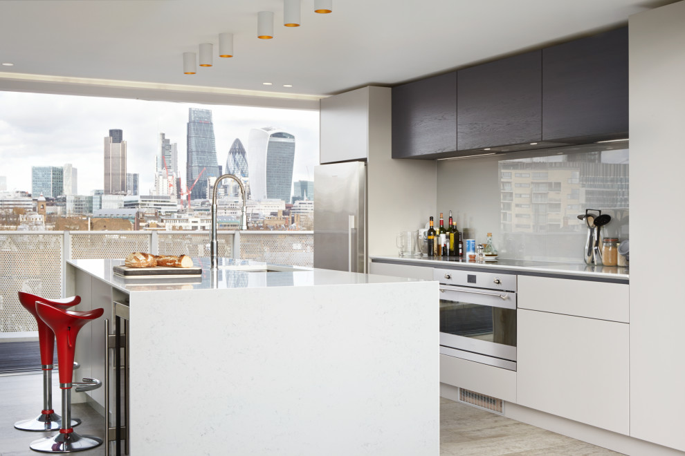 Zweizeilige Moderne Küche mit Unterbauwaschbecken, flächenbündigen Schrankfronten, weißen Schränken, Küchengeräten aus Edelstahl, Kücheninsel, beigem Boden und weißer Arbeitsplatte in London
