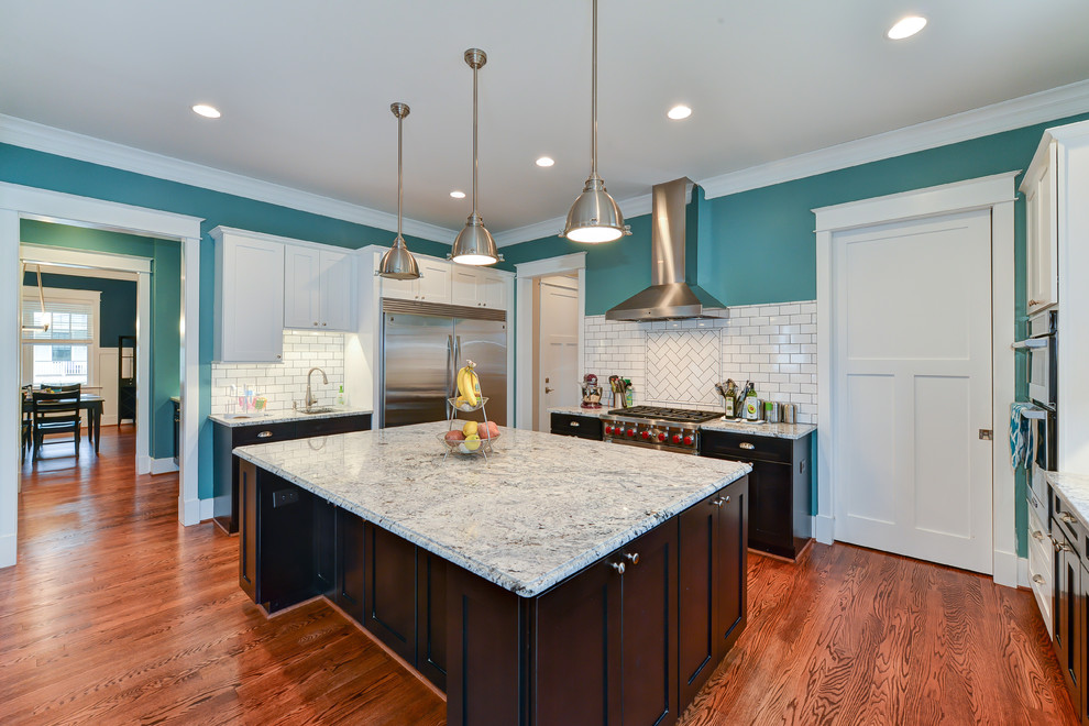 Inspiration for a large craftsman u-shaped medium tone wood floor eat-in kitchen remodel with an undermount sink, recessed-panel cabinets, dark wood cabinets, quartzite countertops, white backsplash, ceramic backsplash, stainless steel appliances and an island