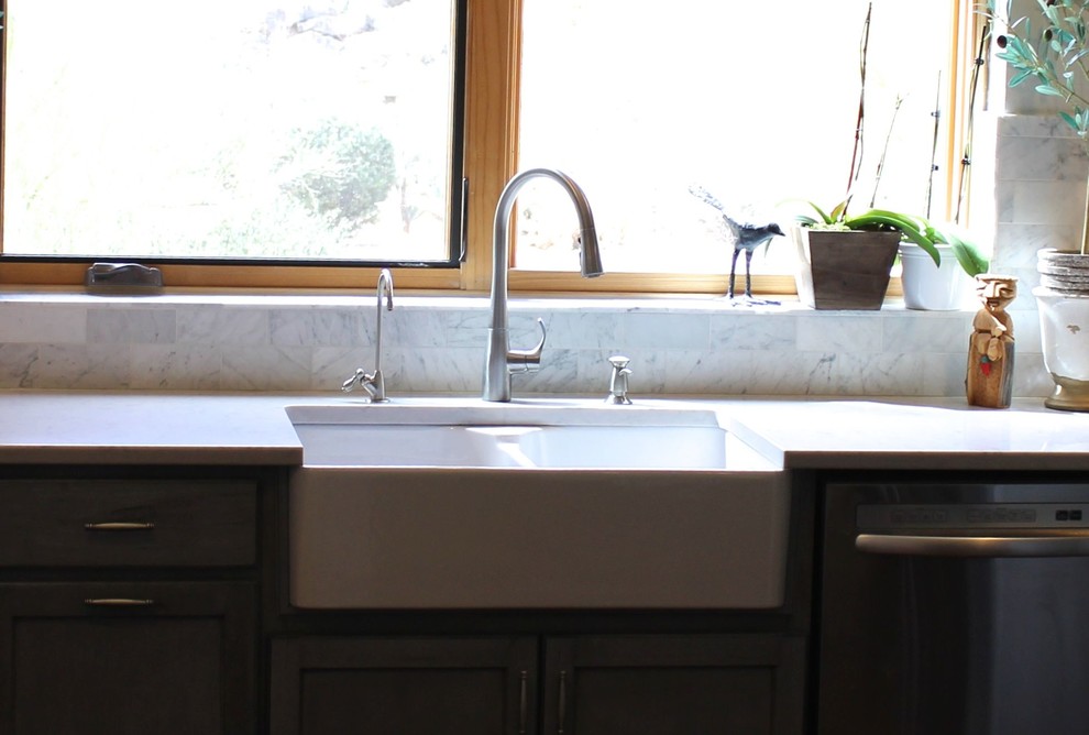 Medelhavsstil inredning av ett mellanstort kök, med en rustik diskho, luckor med infälld panel, grå skåp, bänkskiva i kvarts, vitt stänkskydd, stänkskydd i stenkakel, rostfria vitvaror, travertin golv och en halv köksö