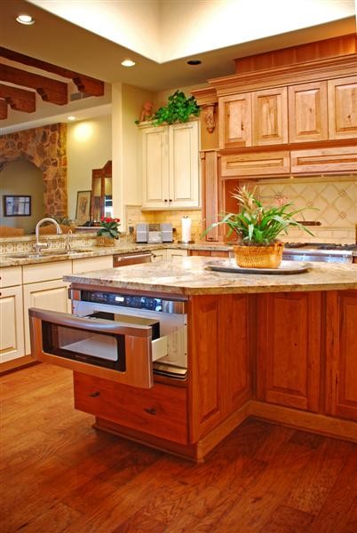 Modelo de cocina extra grande con fregadero bajoencimera, electrodomésticos de acero inoxidable y suelo de madera en tonos medios