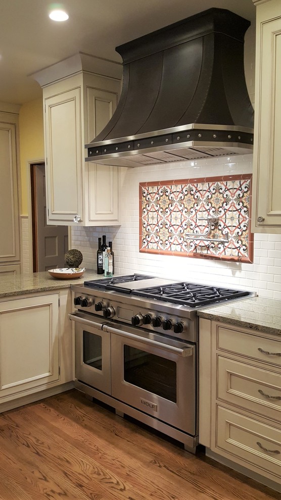 Large ornate l-shaped medium tone wood floor and brown floor enclosed kitchen photo in Seattle with a farmhouse sink, beaded inset cabinets, beige cabinets, granite countertops, beige backsplash, ceramic backsplash, stainless steel appliances, a peninsula and green countertops