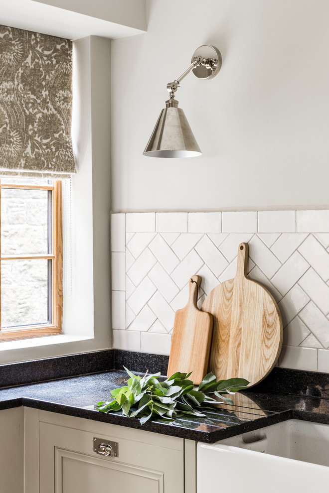 Exempel på ett stort lantligt kök, med en rustik diskho, luckor med profilerade fronter, grå skåp, träbänkskiva, vitt stänkskydd, stänkskydd i keramik, integrerade vitvaror, kalkstensgolv och flerfärgat golv