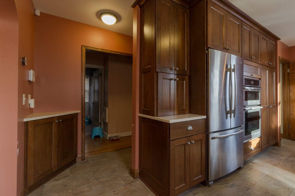 Immagine di una cucina abitabile chic con lavello sottopiano, ante in stile shaker, ante in legno bruno, paraspruzzi con piastrelle in pietra e pavimento in gres porcellanato