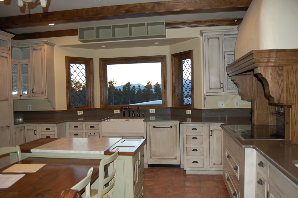 Medium sized traditional u-shaped kitchen/diner in Seattle with a belfast sink, recessed-panel cabinets, distressed cabinets, engineered stone countertops, grey splashback, stone slab splashback, terracotta flooring and an island.