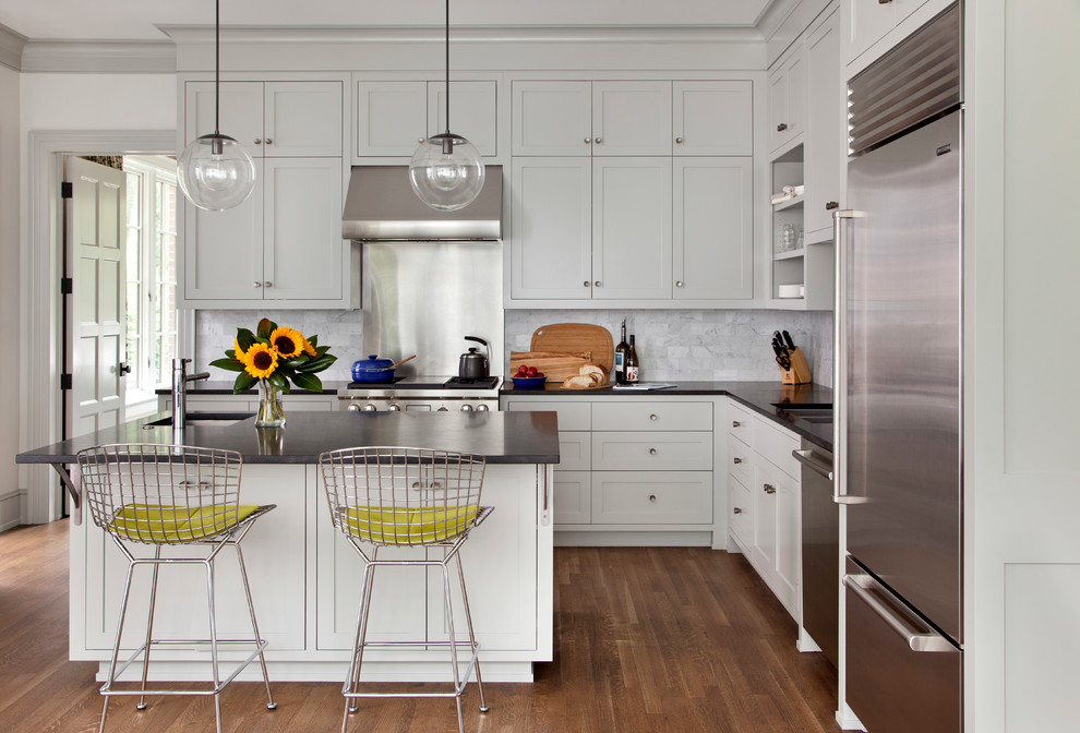 Klassisk inredning av ett kök, med grått stänkskydd, stänkskydd i marmor och rostfria vitvaror