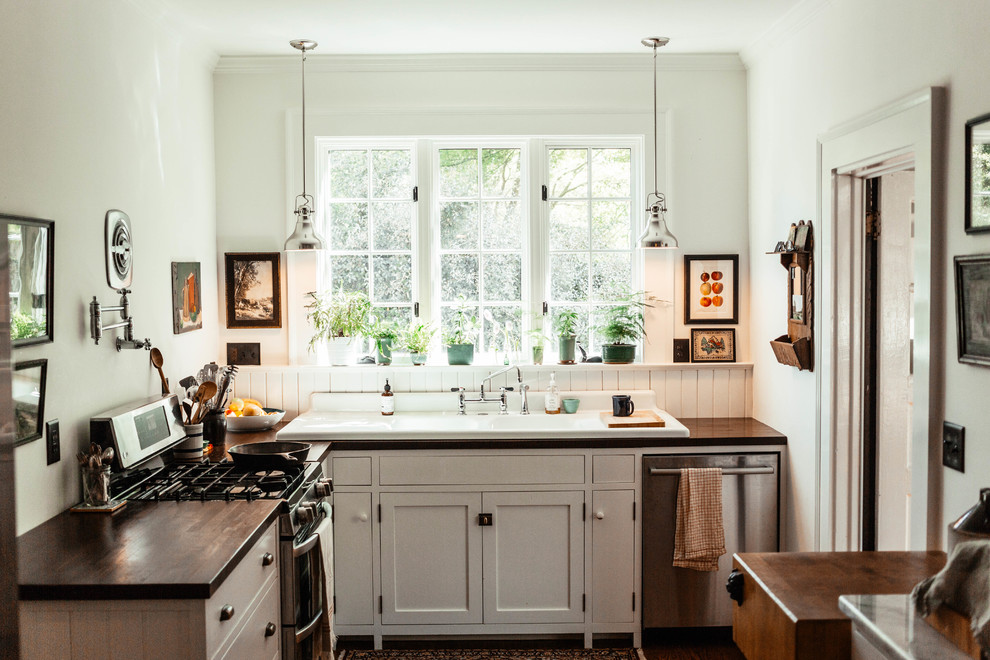 Foto di una cucina a L classica con lavello da incasso, ante in stile shaker, ante bianche, paraspruzzi bianco, elettrodomestici in acciaio inossidabile e nessuna isola
