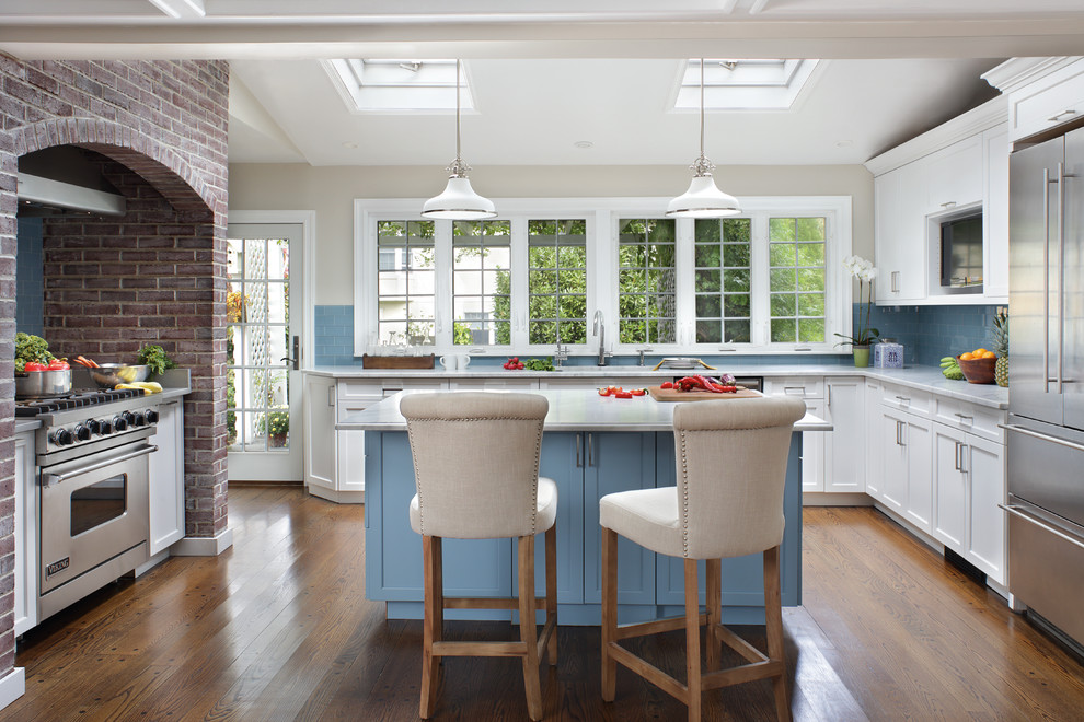 Eat-in kitchen - large transitional l-shaped medium tone wood floor eat-in kitchen idea in New York with recessed-panel cabinets, white cabinets, quartz countertops, blue backsplash, glass tile backsplash, stainless steel appliances, an island and an undermount sink