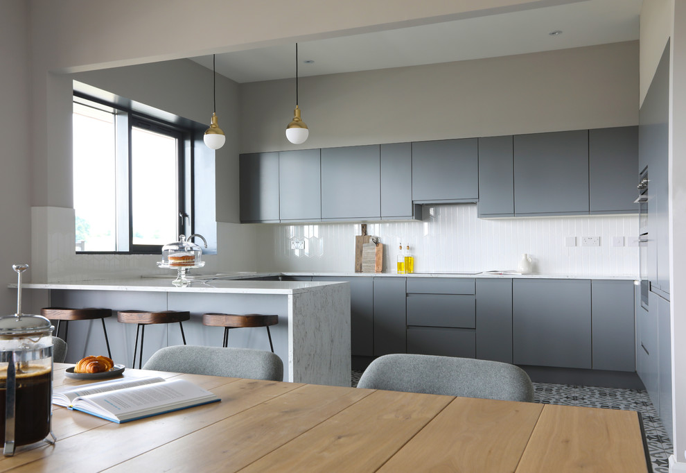 Inspiration for a contemporary l-shaped open plan kitchen in Dublin with a single-bowl sink, flat-panel cabinets, grey cabinets, laminate countertops, white splashback, ceramic splashback, integrated appliances, cement flooring, an island, grey floors and white worktops.