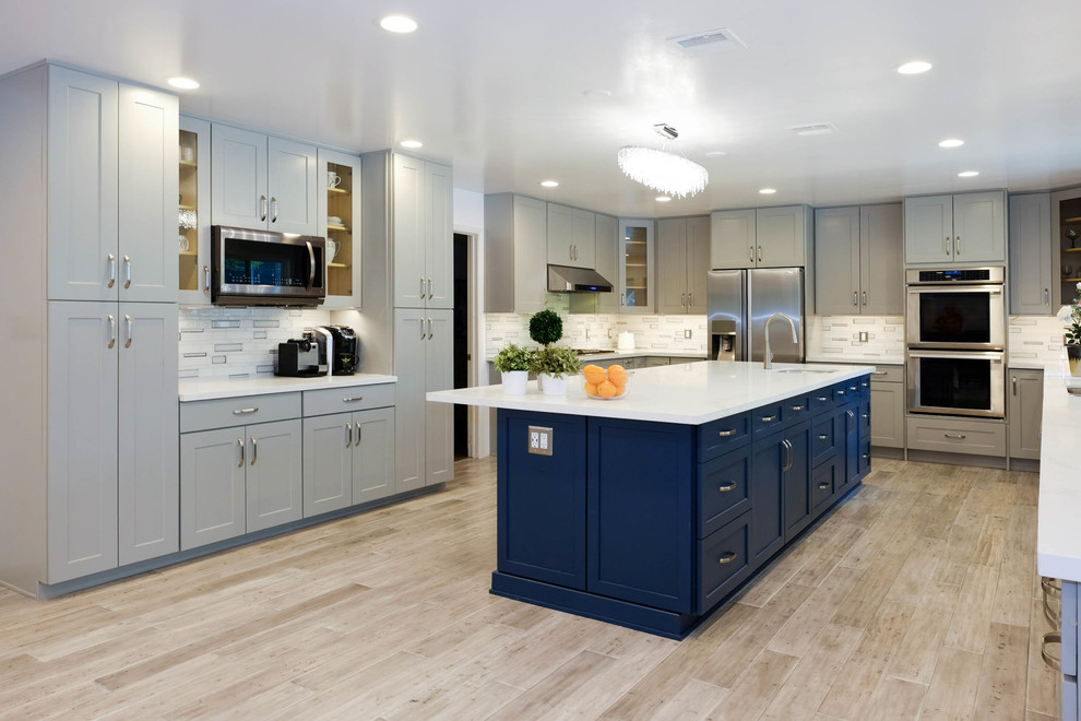 Inspiration for an expansive contemporary u-shaped kitchen/diner in Los Angeles with a built-in sink, shaker cabinets, grey cabinets, engineered stone countertops, multi-coloured splashback, glass tiled splashback, stainless steel appliances, porcelain flooring, an island, beige floors and white worktops.