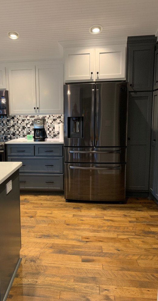 Inredning av ett lantligt vit vitt kök och matrum, med en rustik diskho, skåp i shakerstil, blå skåp, granitbänkskiva, grått stänkskydd, stänkskydd i glaskakel, rostfria vitvaror, mellanmörkt trägolv, en köksö och brunt golv