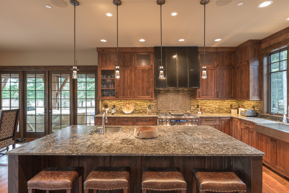 This is an example of a rustic l-shaped kitchen/diner in Seattle with stainless steel appliances, medium hardwood flooring, an island, a belfast sink, shaker cabinets, dark wood cabinets, multi-coloured splashback and matchstick tiled splashback.