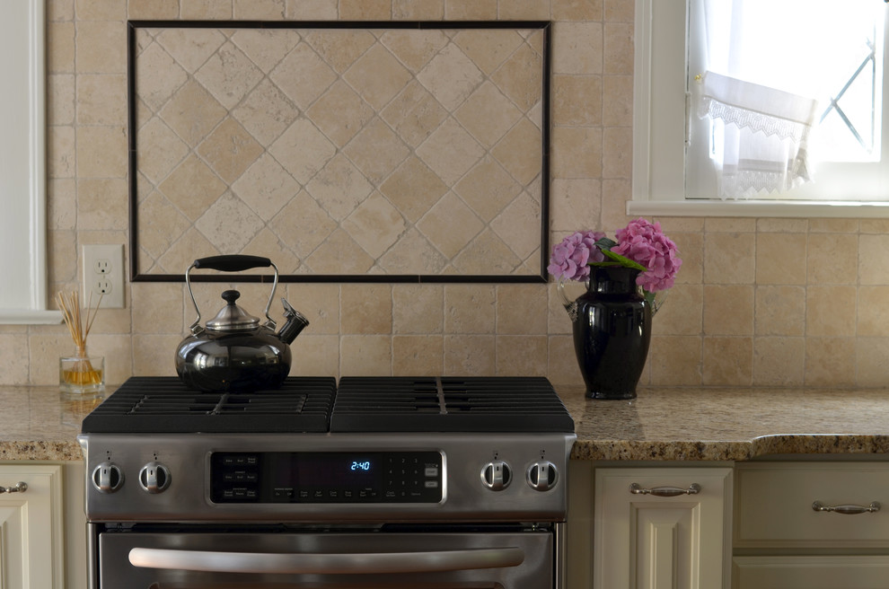 Klassisk inredning av ett mellanstort kök och matrum, med luckor med upphöjd panel, vita skåp, granitbänkskiva, beige stänkskydd, stänkskydd i stenkakel och rostfria vitvaror