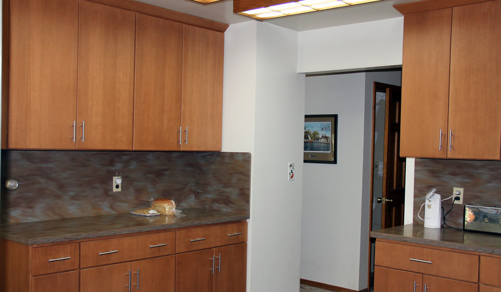Cette photo montre une cuisine américaine moderne en bois brun de taille moyenne avec un évier encastré, un placard à porte plane, un plan de travail en surface solide, un électroménager en acier inoxydable et une péninsule.