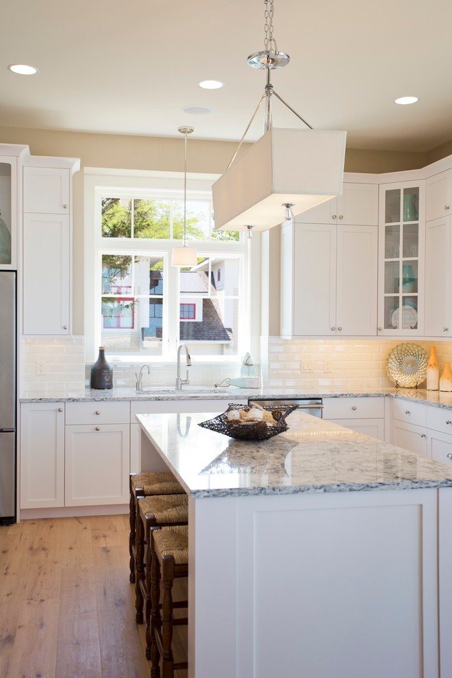 Inspiration for a large coastal u-shaped light wood floor kitchen remodel in Grand Rapids with a double-bowl sink, recessed-panel cabinets, white cabinets, granite countertops, stainless steel appliances and an island