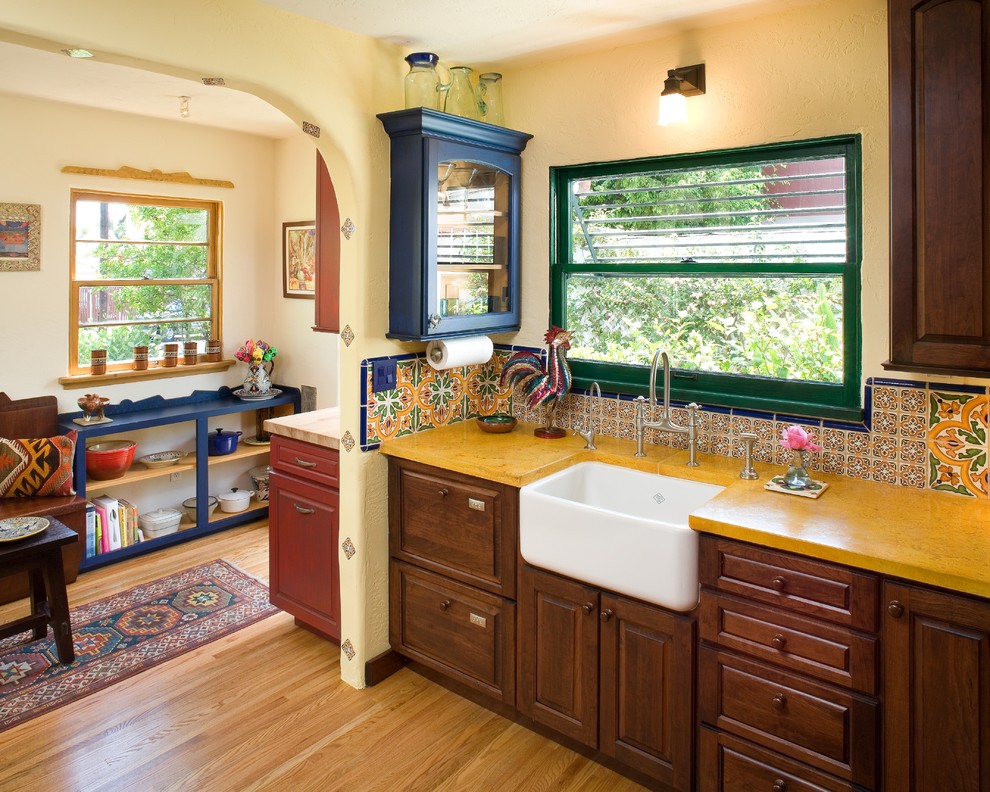 На фото: кухня в средиземноморском стиле с разноцветным фартуком, с полувстраиваемой мойкой (с передним бортиком), фасадами с выступающей филенкой, темными деревянными фасадами и окном с